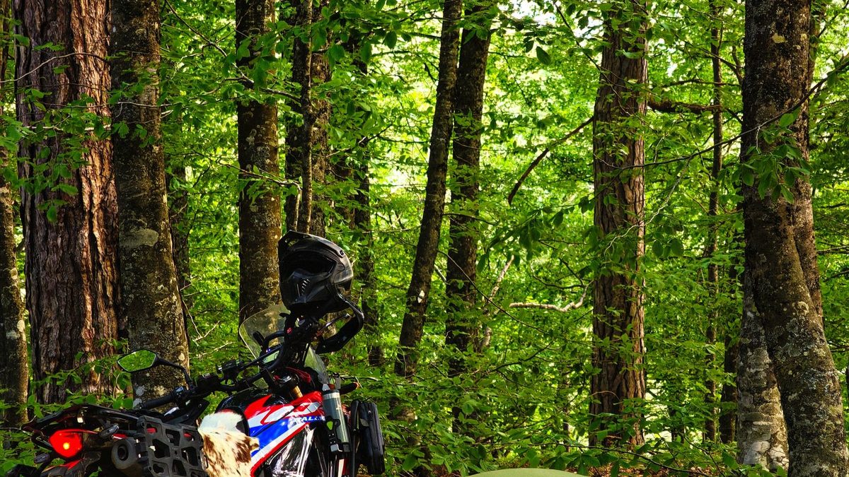 Motorcycle touring comparison showing a campsite tent next to a motel room for overnight stay planning