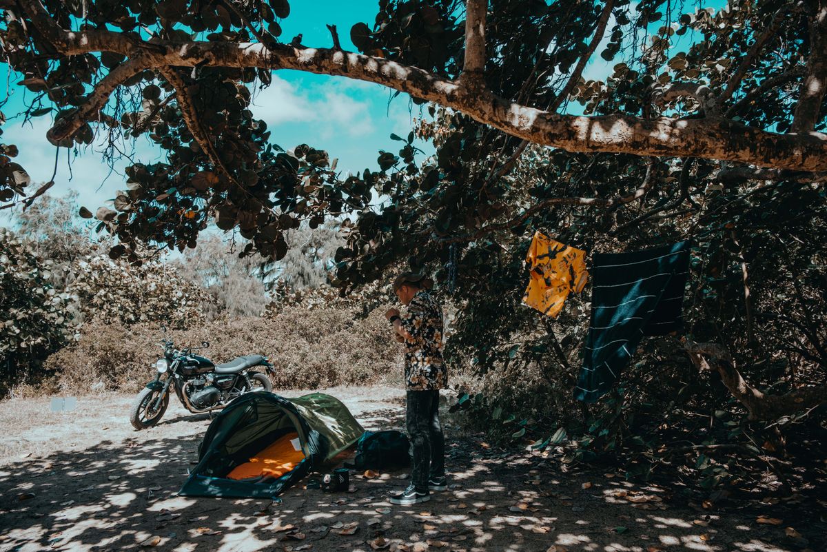 Motorcycle camping setup in forest with tent and gear