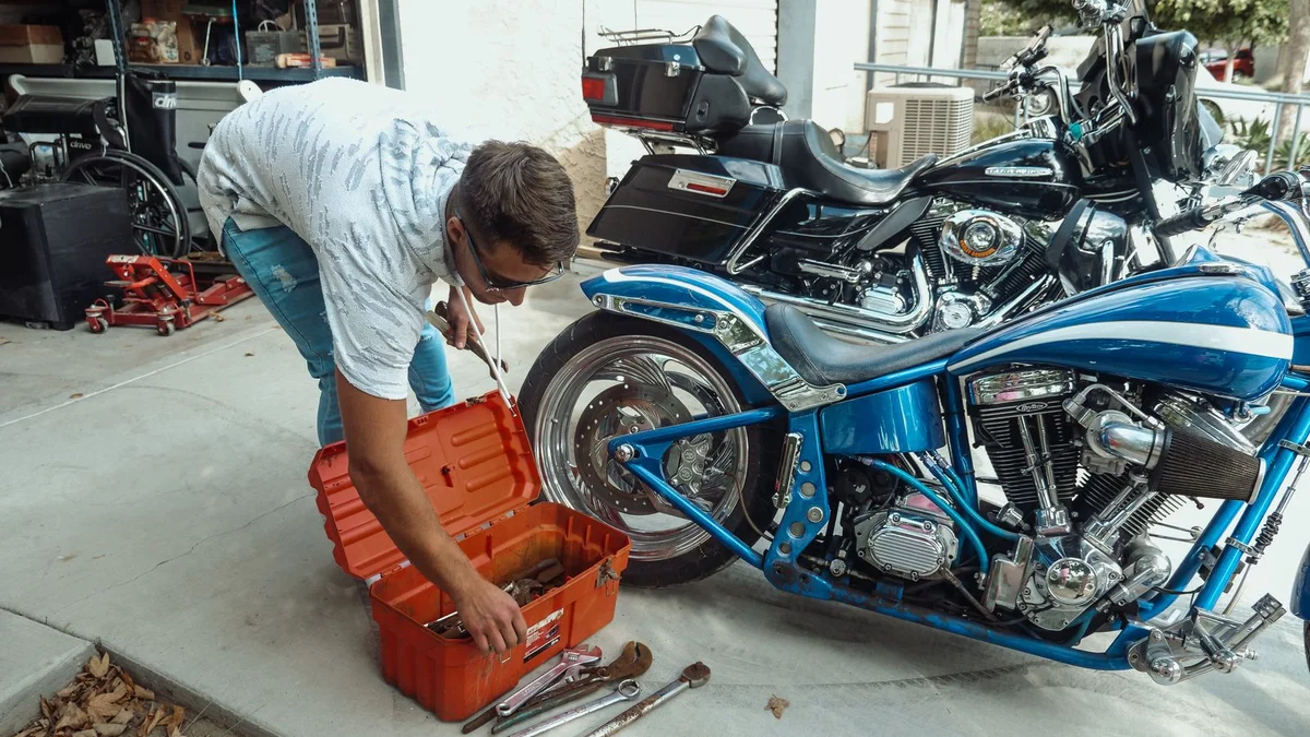 Mechanic working on a motorcycle in a garage with tools representing rising parts and service costs from US-Canada tariffs in 2026